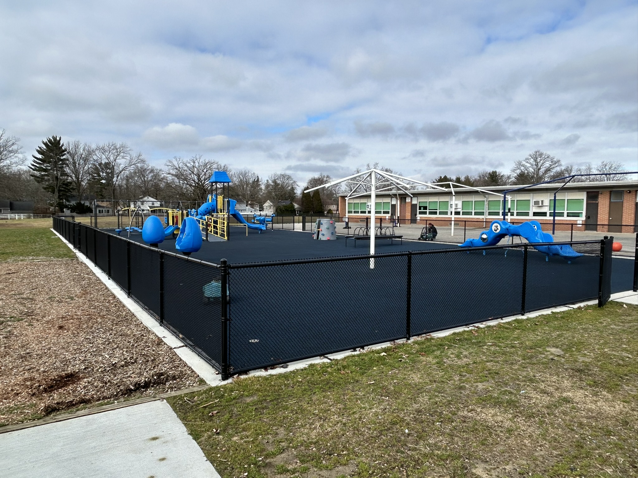 NACOM project scope included demolition of dated playground, fence, and paving. A new ADA playground with ramps and subbase was installed for new playground equipment, along with installation of new perimeter fencing with gates and connection to existing building. Project included subdrainage, with storm connection from existing roof drains. The new ADA ramps improved accessibility from the school and public parking areas.